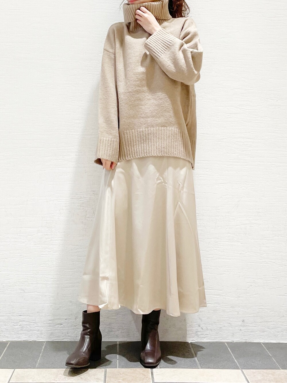 ブラウン系のブーツ、ホワイト系のスカート、ベージュ系のニット/セーターを着用したレディースの冬コーディネートの3枚目の写真