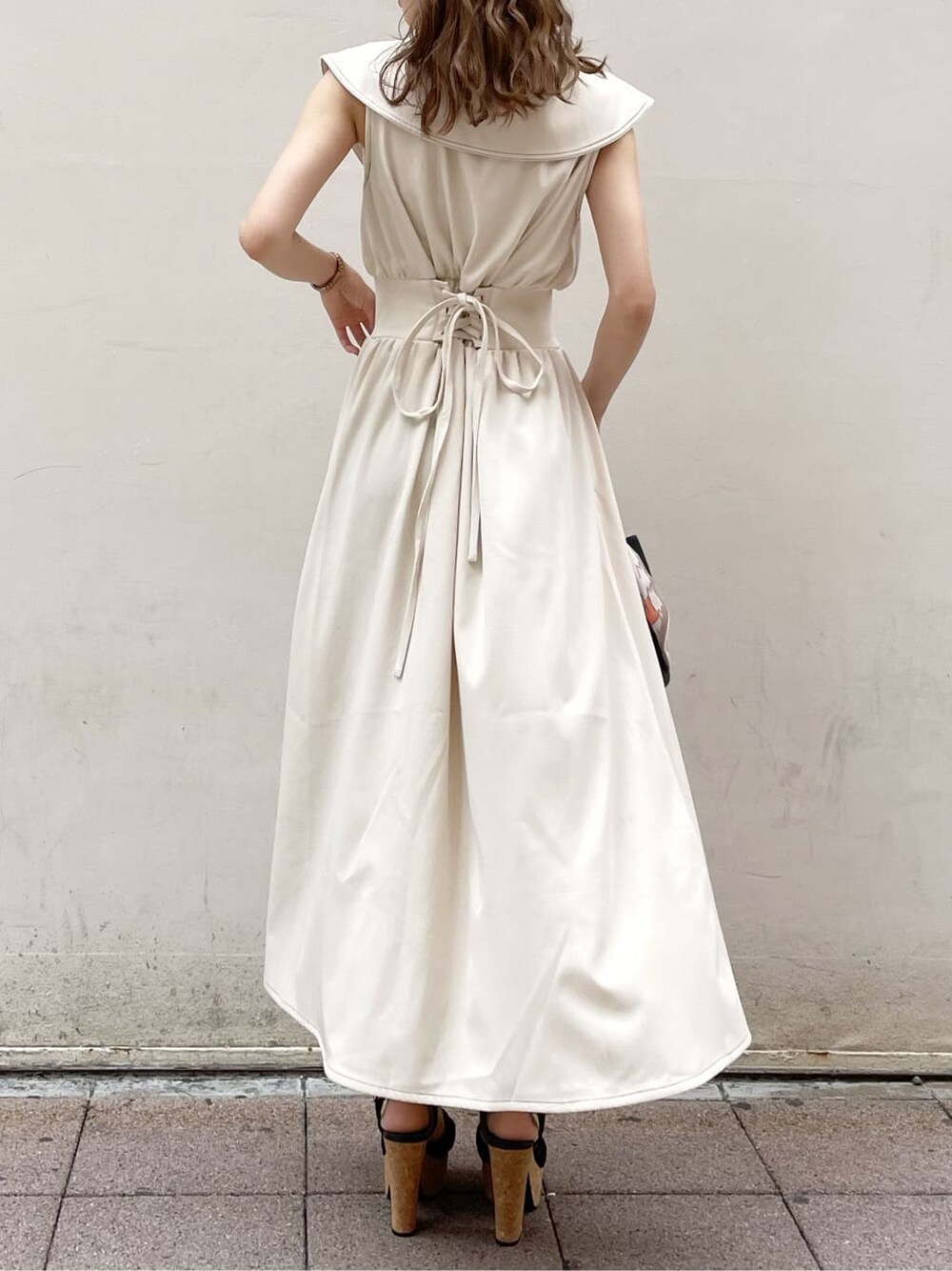 ブラック系のサンダル、ブラック系のハンドバッグ、ホワイト系のワンピースを着用したレディースの春コーディネートの2枚目の写真