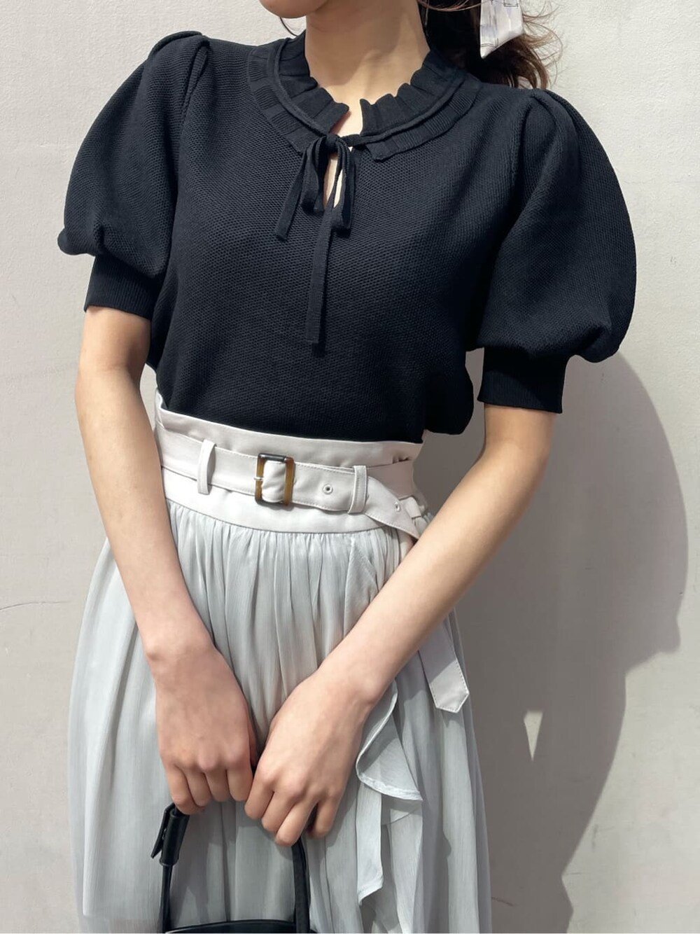 グレー系のスカート、ブラック系のサンダル、ホワイト系のニット/セーターを着用したレディースの春コーディネートの4枚目の写真