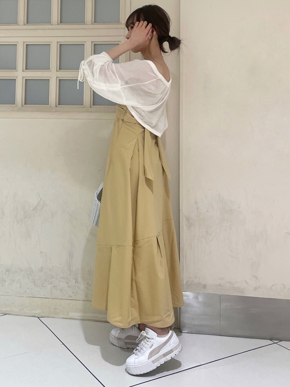 ホワイト系のカーディガン/ボレロ、イエロー系のワンピース、ホワイト系のハンドバッグを着用したレディースの夏コーディネートの2枚目の写真