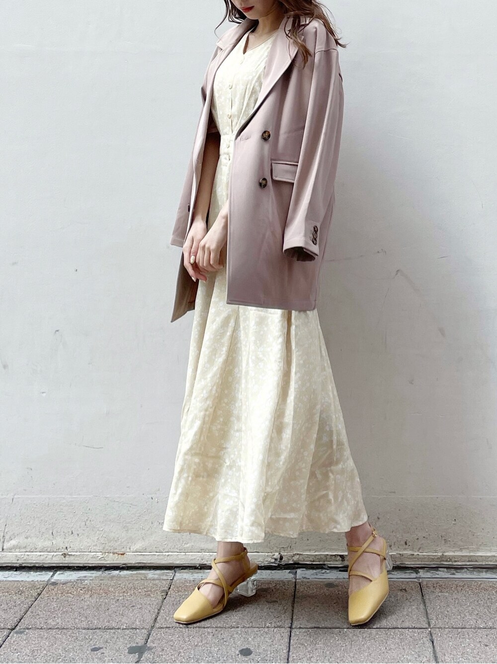 ベージュ系のテーラードジャケット、イエロー系のワンピース、イエロー系のパンプスを着用したレディースの春コーディネートの2枚目の写真