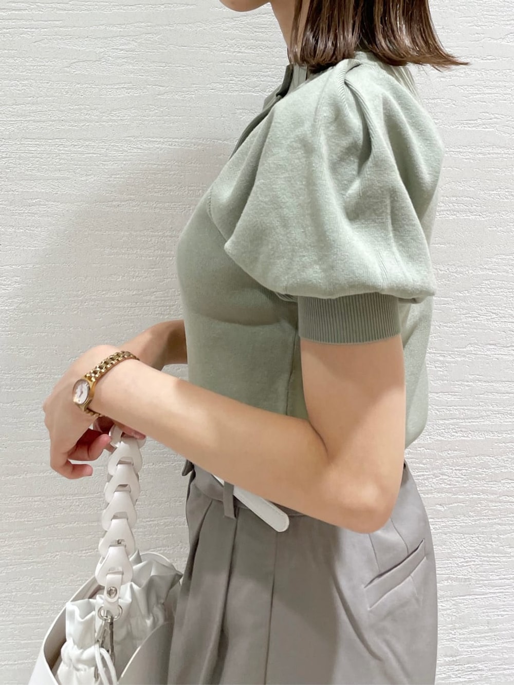 グレー系のその他パンツ、ホワイト系のハンドバッグ、グリーン系のニット/セーターを着用したレディースの夏コーディネートの5枚目の写真