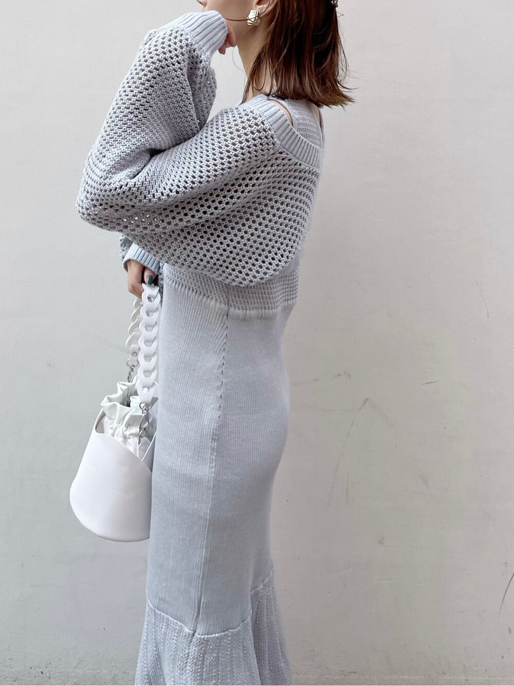 グレー系のワンピース、ホワイト系のハンドバッグ、ベージュ系のブーツを着用したレディースの秋コーディネートの6枚目の写真