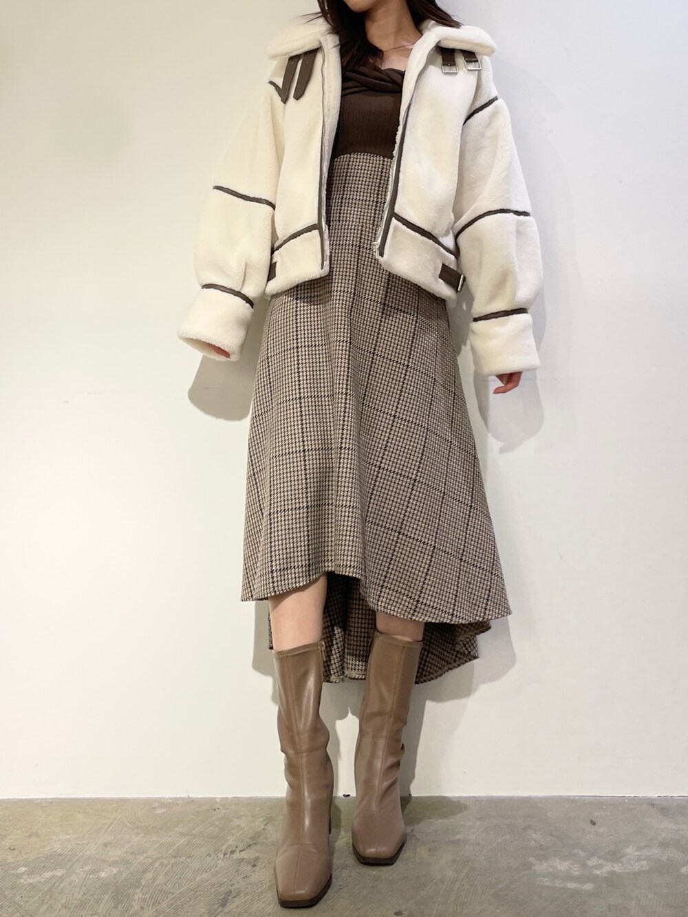 ブラウン系のワンピース、ベージュ系のブーツ、ホワイト系のブルゾンを着用したレディースの秋コーディネートの3枚目の写真