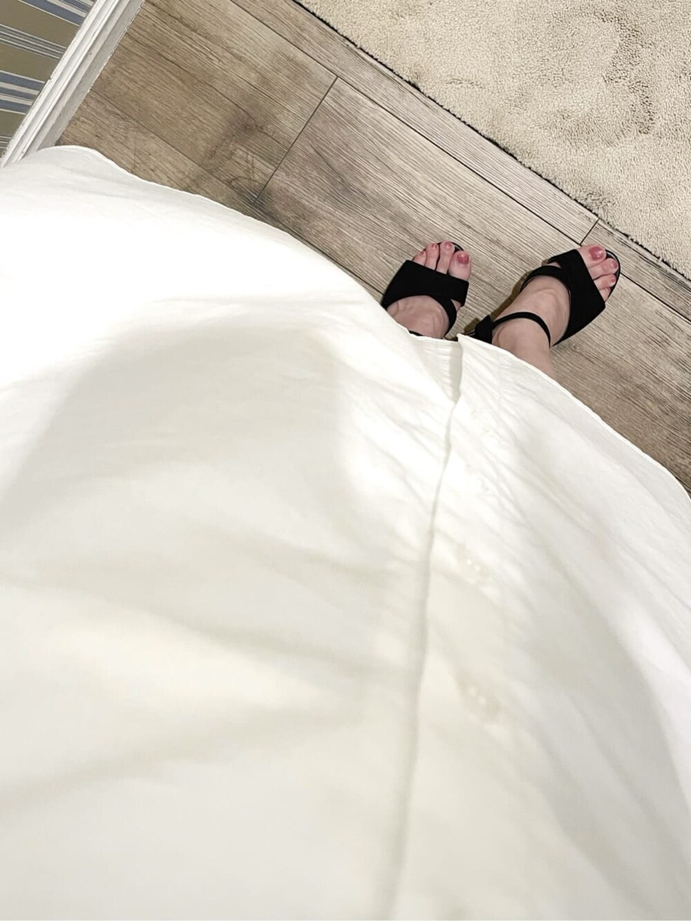 ブラック系のサンダル、ホワイト系のシャツワンピース、ブラウン系のイヤリングを着用したレディースの夏コーディネートの8枚目の写真