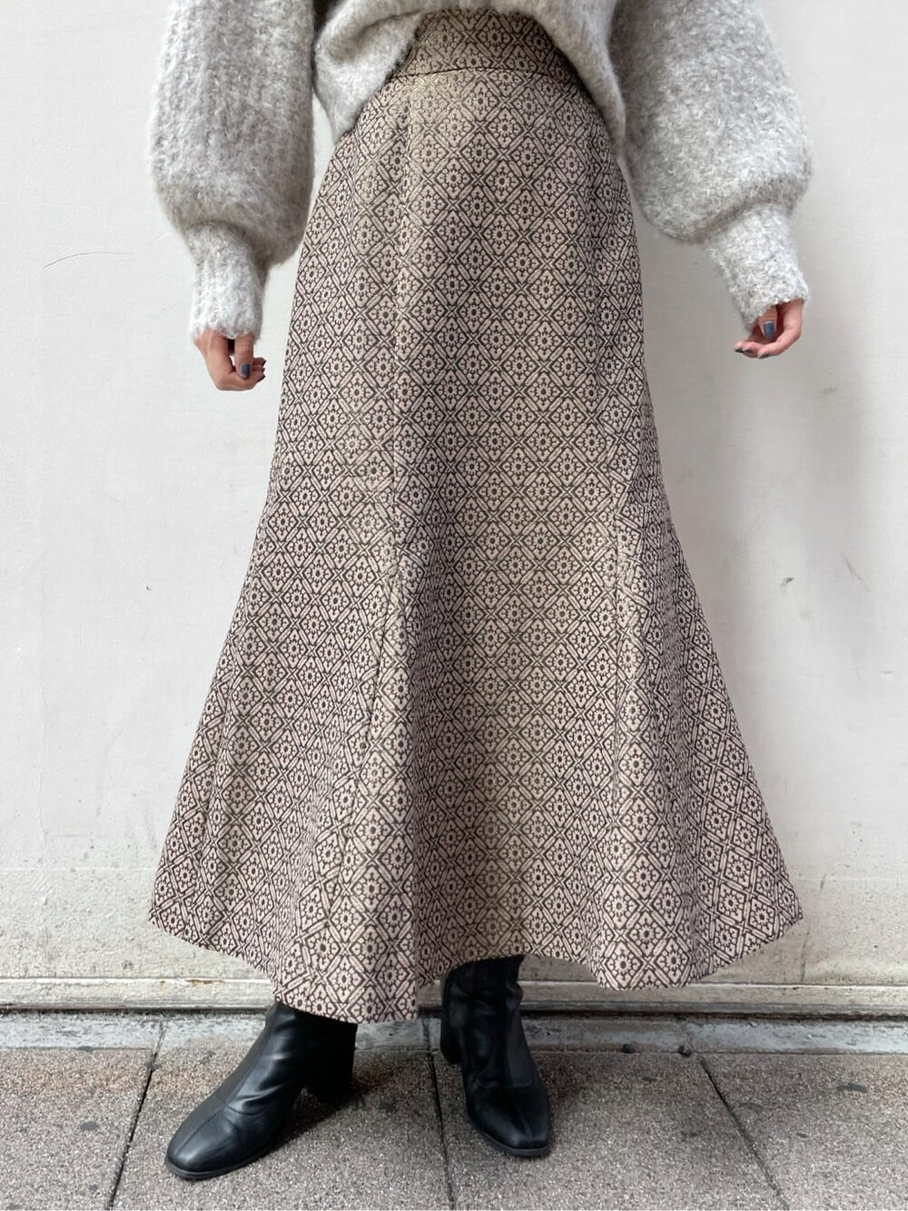 ブラック系のブーツ、ベージュ系のニット/セーター、ゴールド系のスカートを着用したレディースの秋コーディネートの9枚目の写真