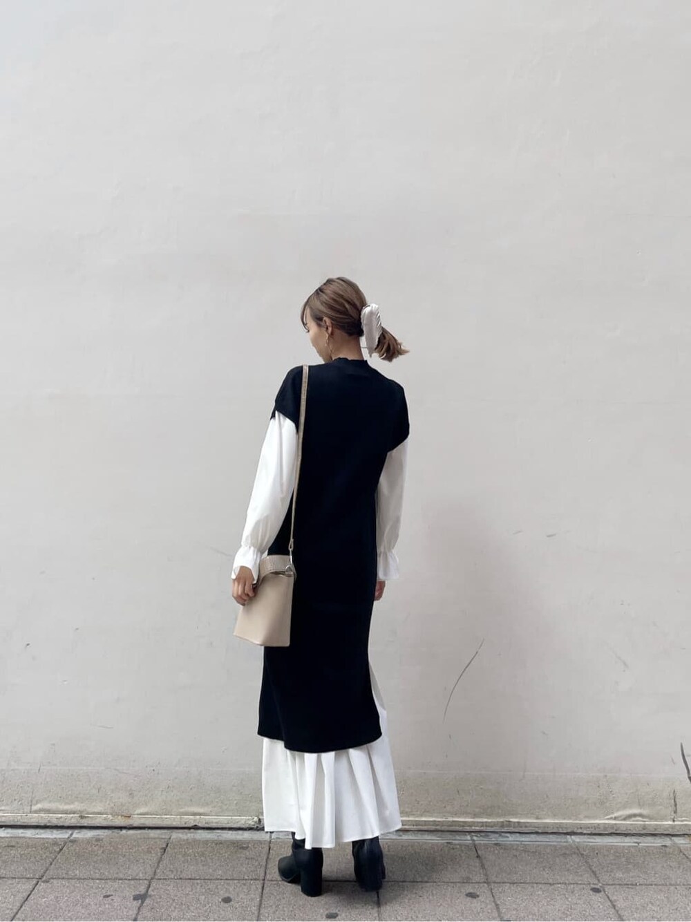 ブラック系のブーツ、ブラック系のワンピース、ベージュ系のハンドバッグを着用したレディースの秋コーディネートの2枚目の写真