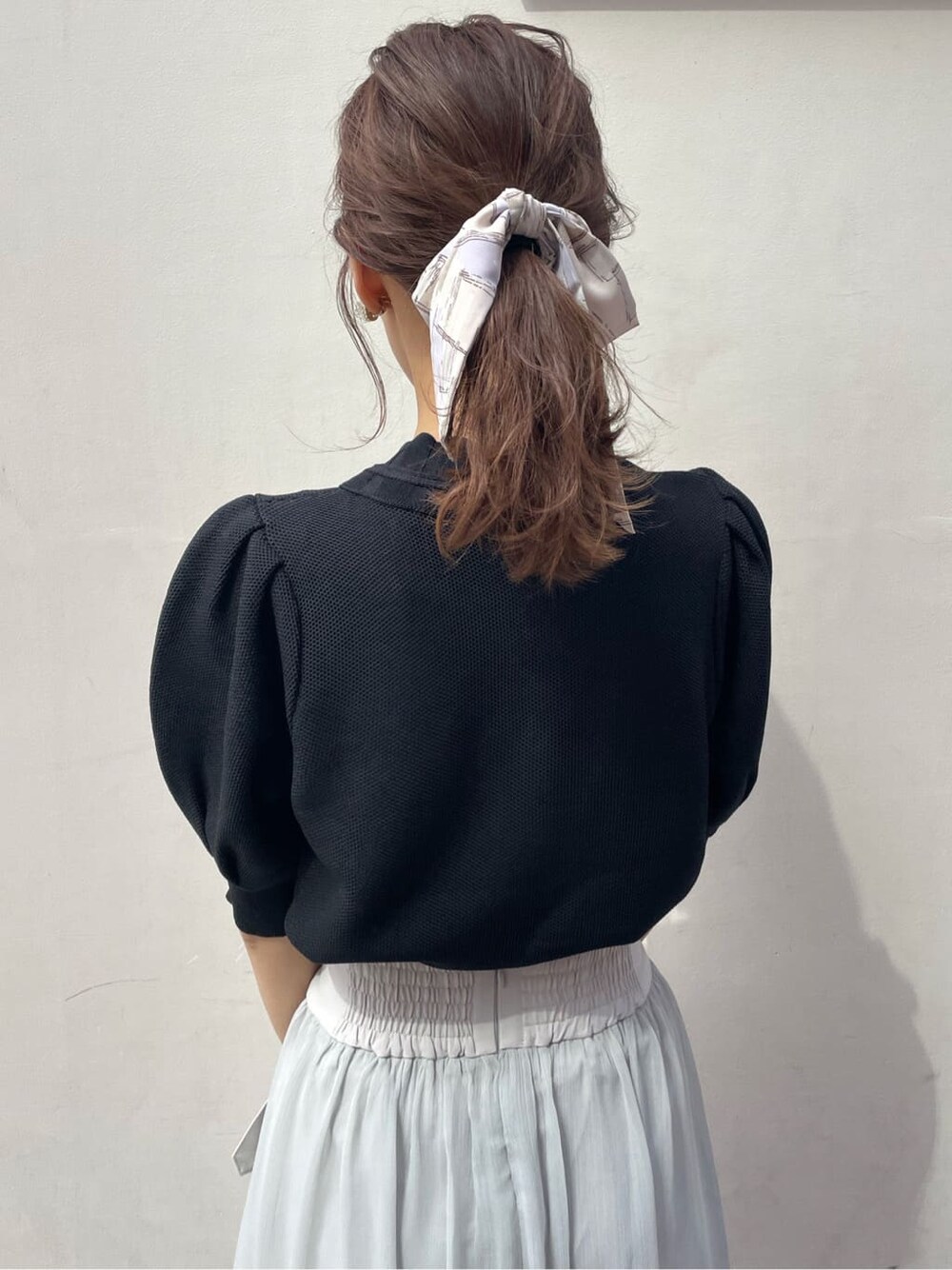 グレー系のスカート、ブラック系のサンダル、ホワイト系のニット/セーターを着用したレディースの春コーディネートの5枚目の写真