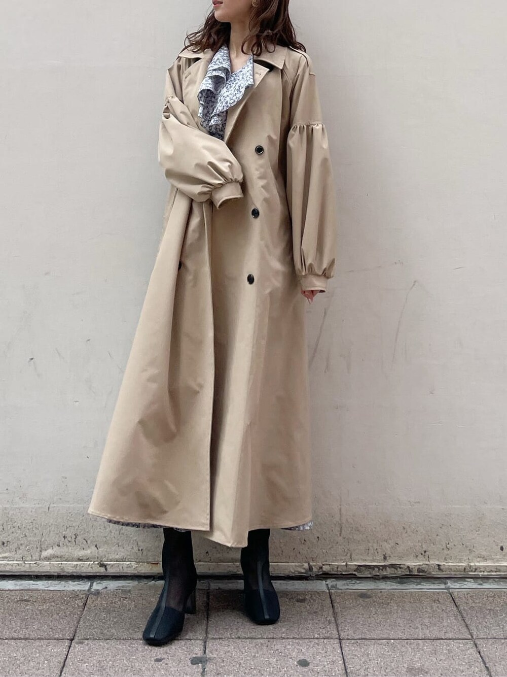 ベージュ系のトレンチコート、ブルー系のワンピース、ブラック系のブーツを着用したレディースの冬コーディネートの3枚目の写真