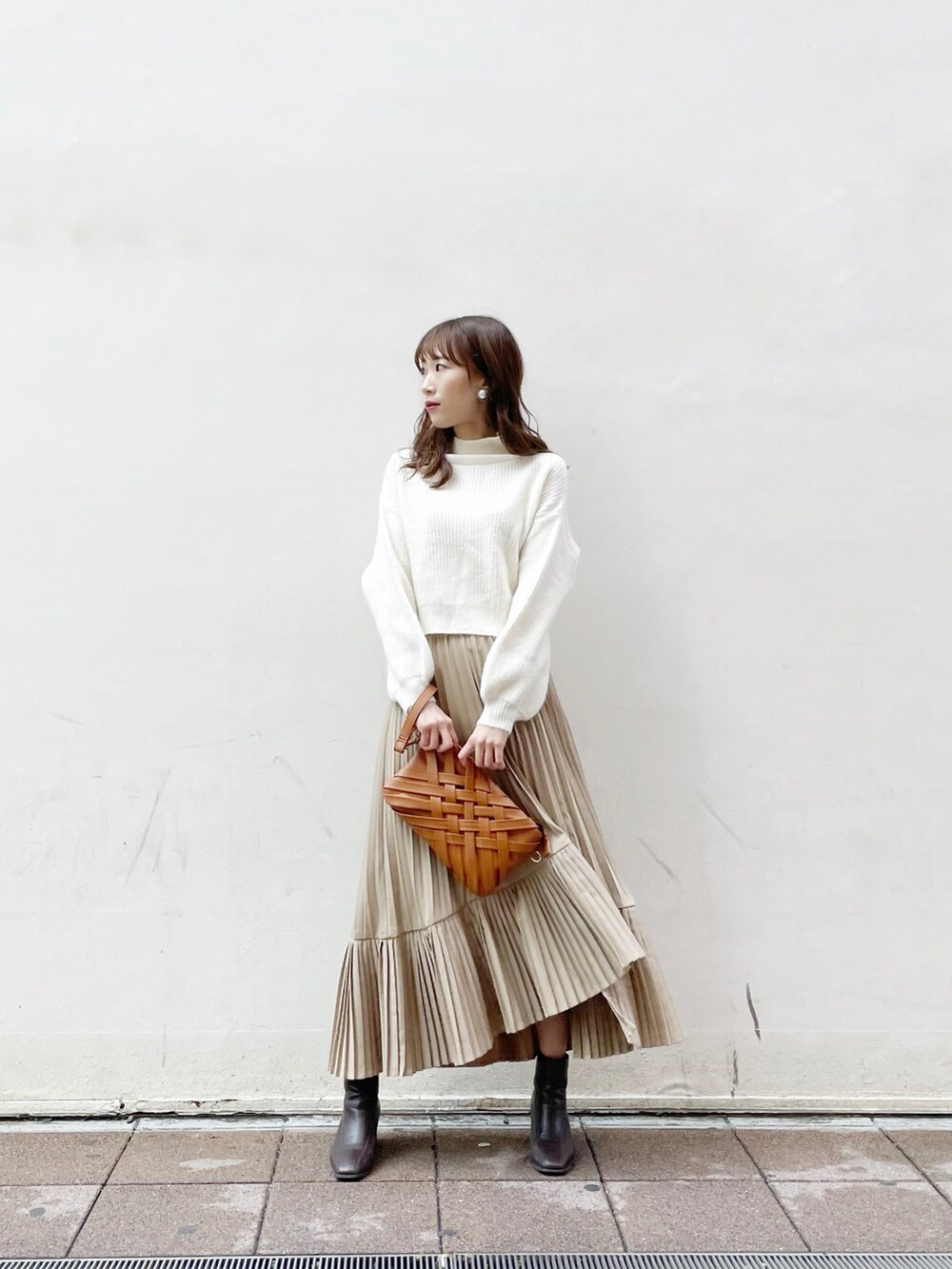 ブラウン系のクラッチバッグ、ホワイト系のニット/セーター、ブラウン系のブーツを着用したレディースの冬コーディネートの2枚目の写真