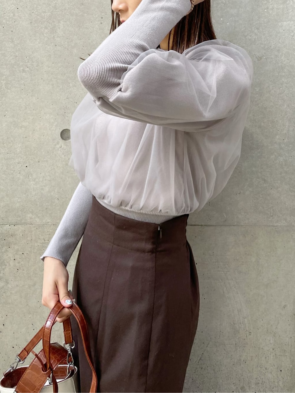 グレー系のニット/セーター、ブラック系のブーツ、ブラウン系のスカートを着用したレディースの秋コーディネートの5枚目の写真