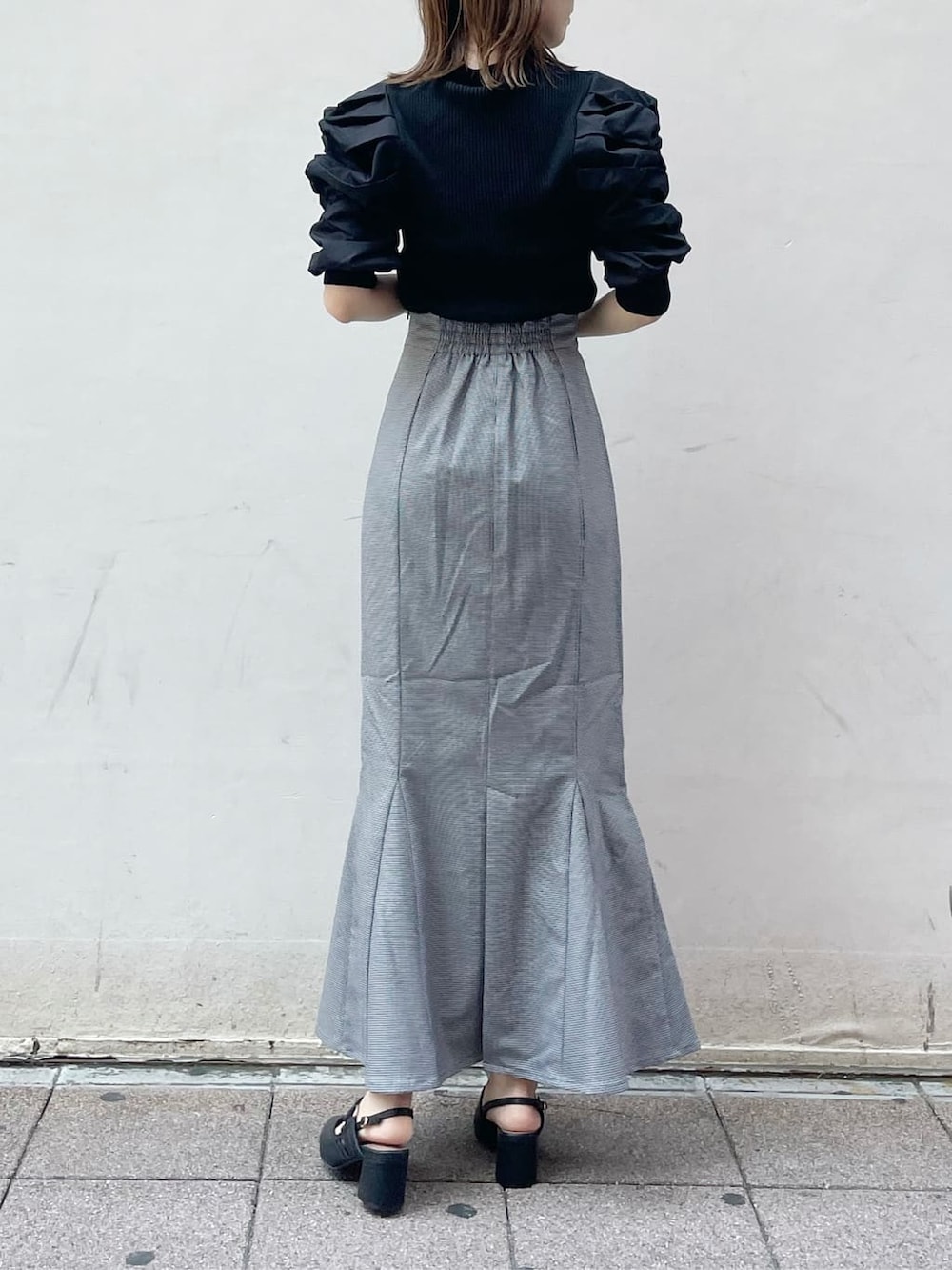 ブラック系のスカート、ブラック系のニット/セーター、ブラック系のハンドバッグを着用したレディースの秋コーディネートの3枚目の写真