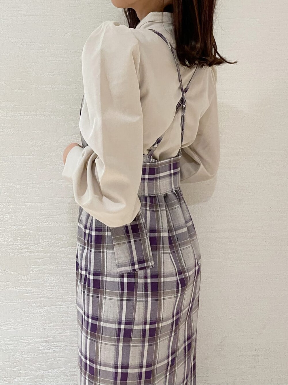 ブラック系のブーツ、ホワイト系のチェスターコート、パープル系のジャンパースカートを着用したレディースの冬コーディネートの7枚目の写真