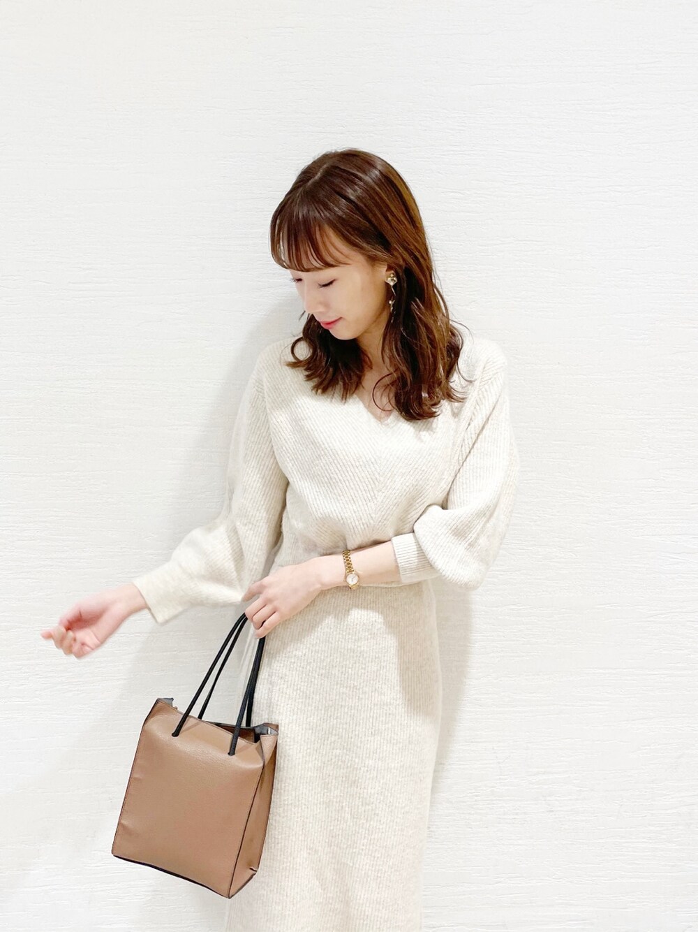 ブラウン系のブーツ、ブラウン系のハンドバッグ、ベージュ系のワンピースを着用したレディースの冬コーディネートの3枚目の写真