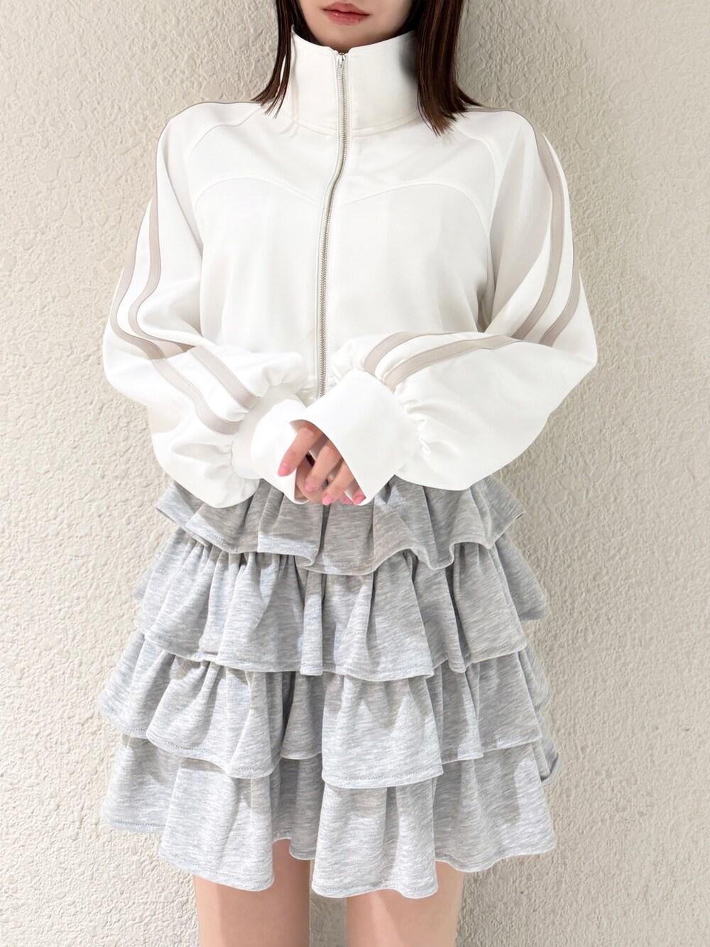 ブラック系のブーツ、グレー系のスカート、ホワイト系のその他アウターを着用したレディースの春コーディネートの4枚目の写真