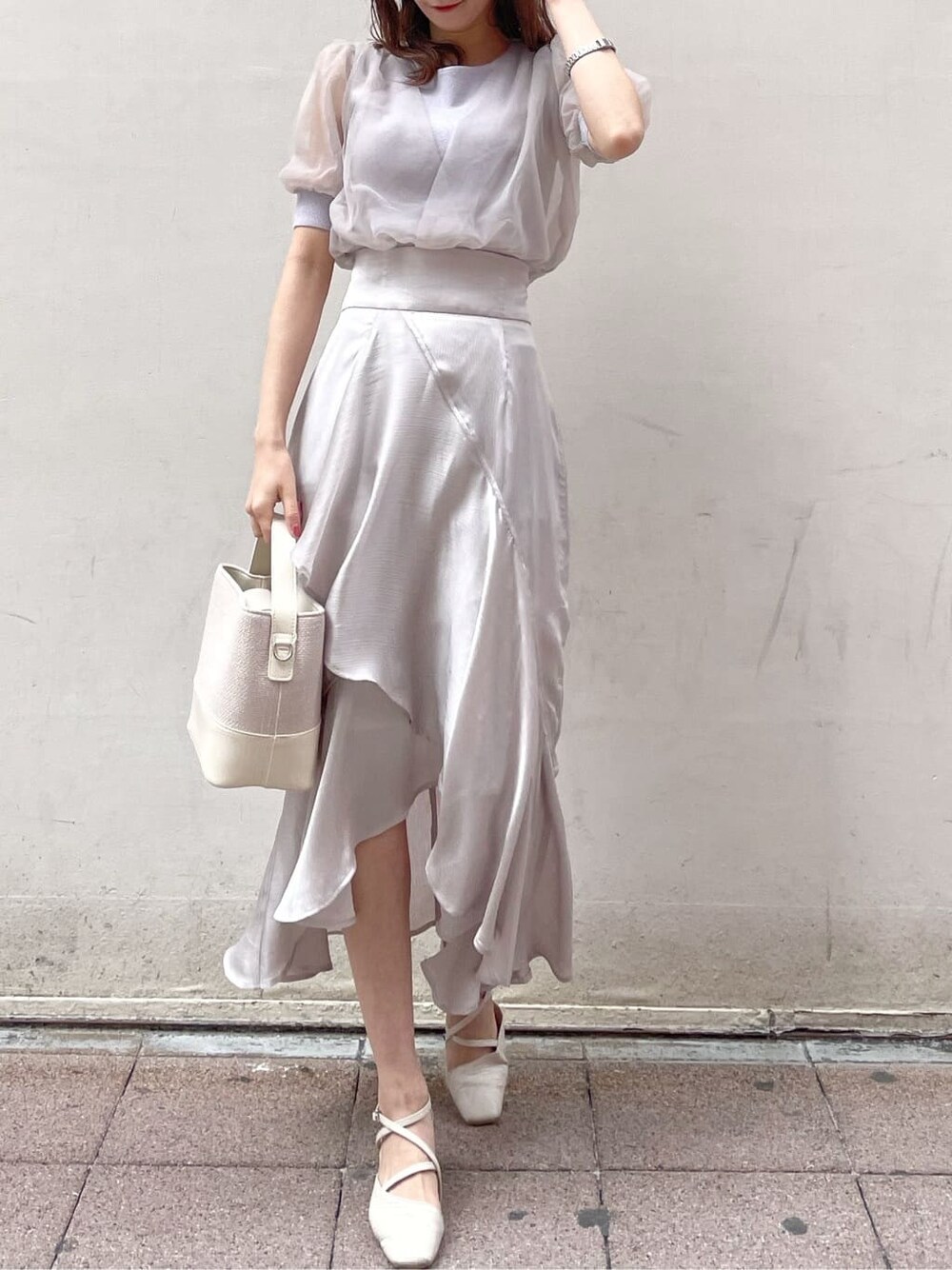 パープル系のニット/セーター、グレー系のスカート、ホワイト系のパンプスを着用したレディースの春コーディネートの2枚目の写真