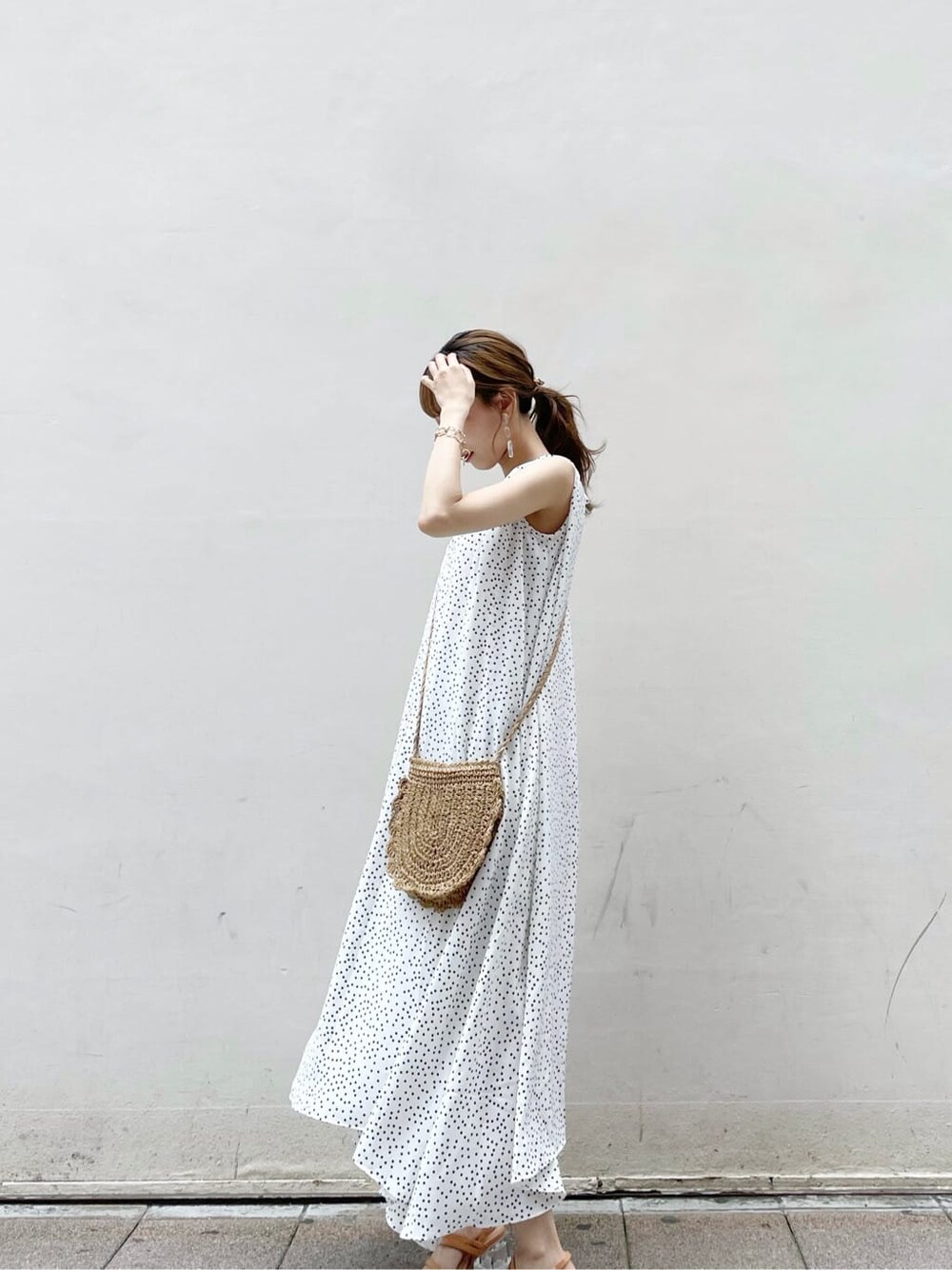 オレンジ系のサンダル、ホワイト系のワンピース、ゴールド系のブレスレットを着用したレディースの夏コーディネートの3枚目の写真