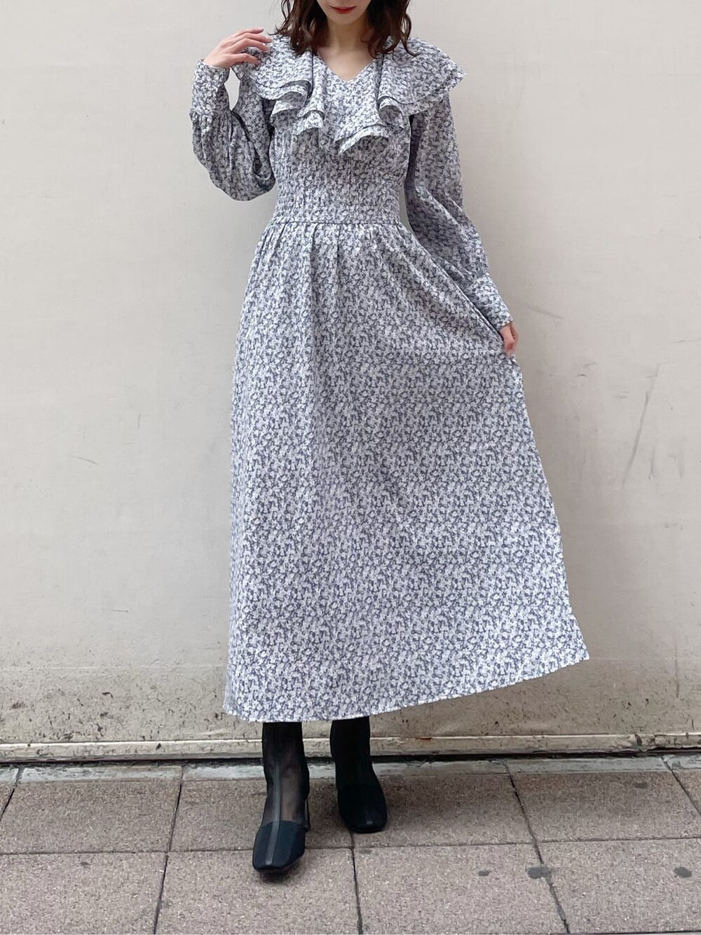 ベージュ系のトレンチコート、ブルー系のワンピース、ブラック系のブーツを着用したレディースの冬コーディネートの5枚目の写真