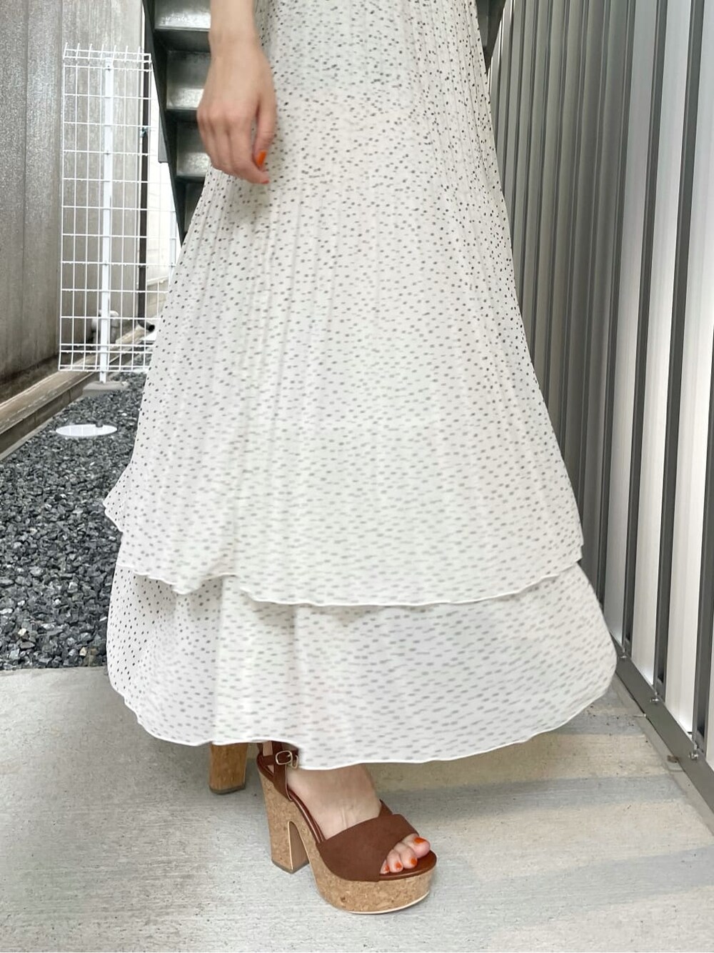 ブラウン系のサンダル、ブラウン系のハンドバッグ、ホワイト系のスカートを着用したレディースの夏コーディネートの9枚目の写真