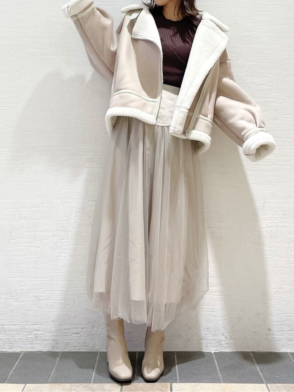 ベージュ系のスカート、ホワイト系のブルゾン、ブラウン系のニット/セーターを着用したレディースの夏コーディネートの2枚目の写真