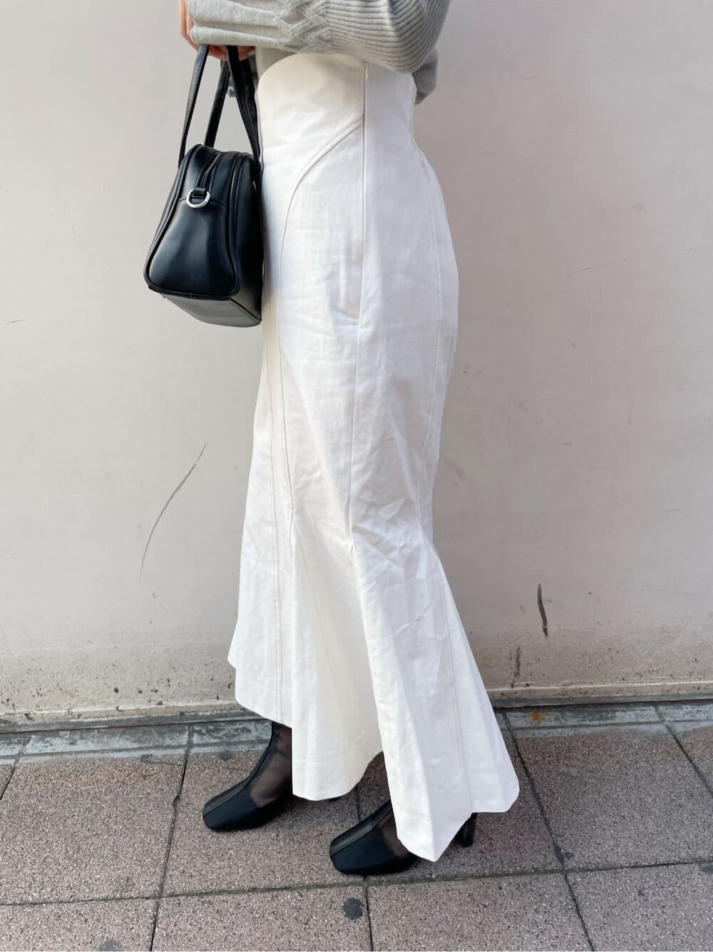 ホワイト系のスカート、ブラック系のブーツ、グリーン系のニット/セーターを着用したレディースの冬コーディネートの8枚目の写真