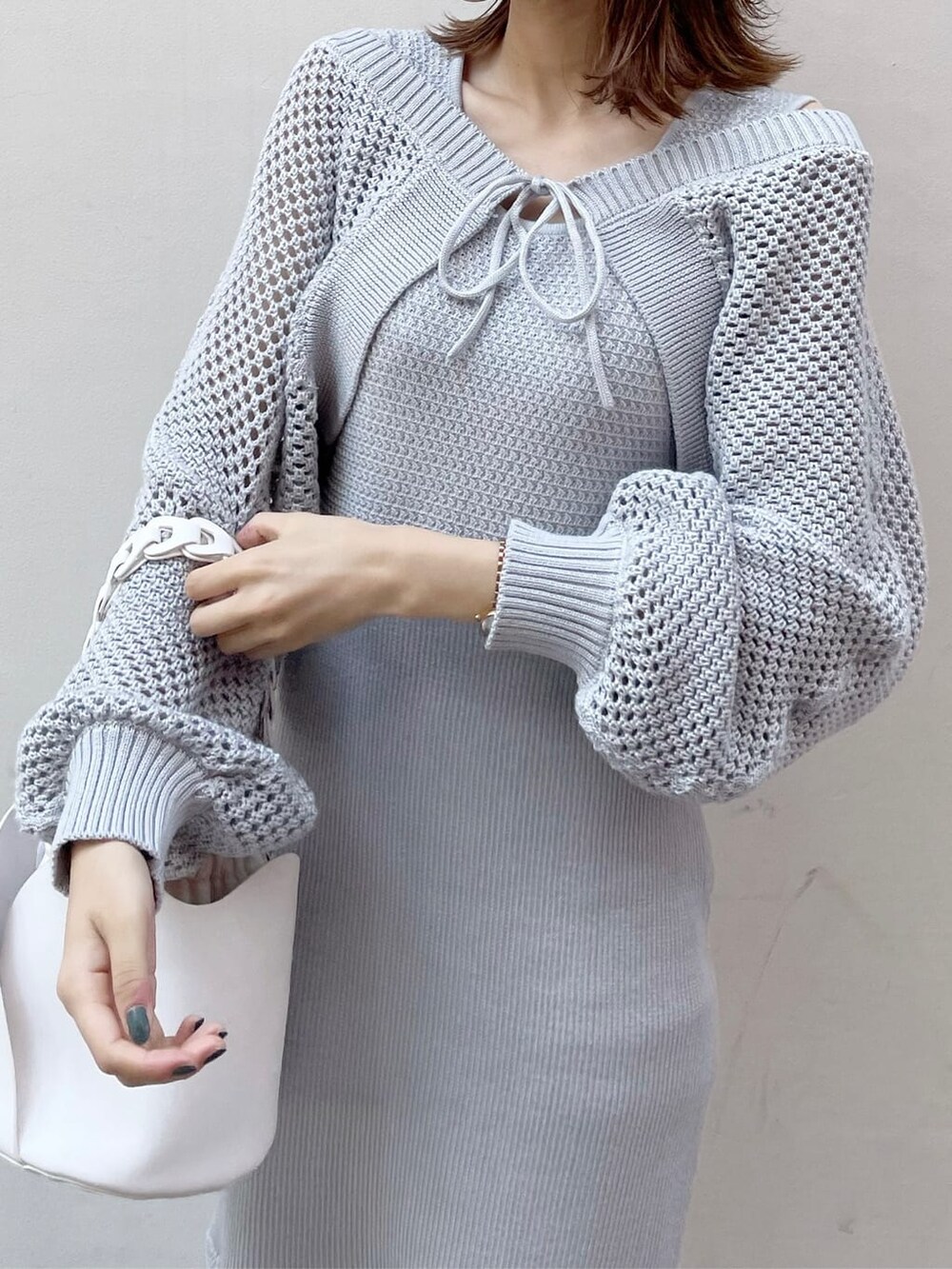 グレー系のワンピース、ホワイト系のハンドバッグ、ベージュ系のブーツを着用したレディースの秋コーディネートの5枚目の写真