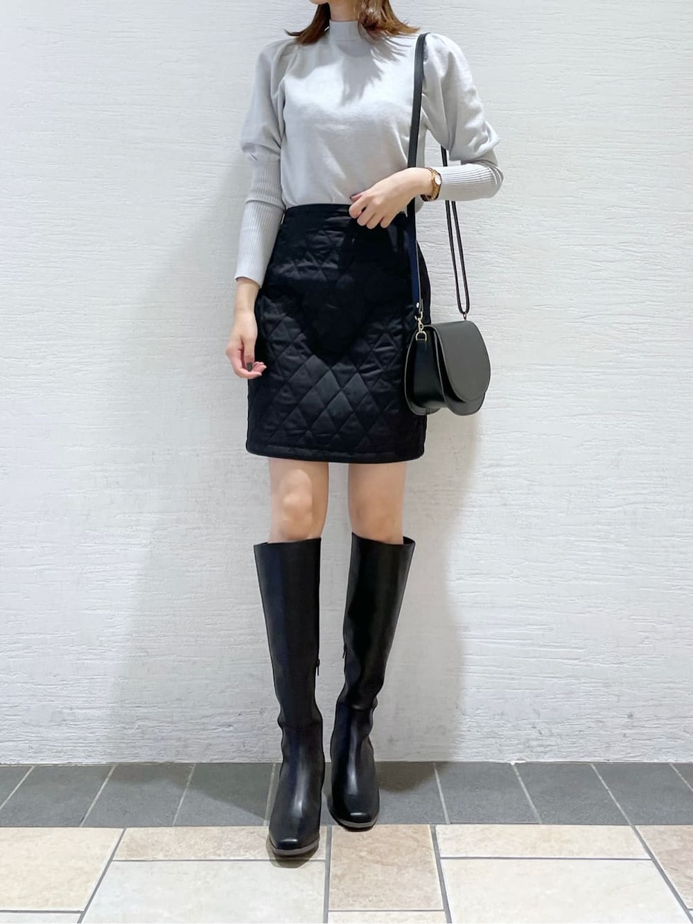 ブラック系のスカート、ブラック系のショルダーバッグ、グレー系のニット/セーターを着用したレディースの秋コーディネートの2枚目の写真