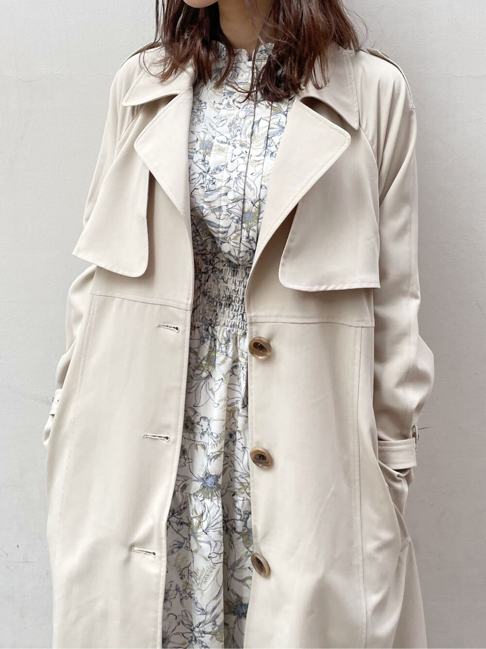 ベージュ系のトレンチコート、ホワイト系のワンピース、ベージュ系のブーツを着用したレディースの春コーディネートの3枚目の写真