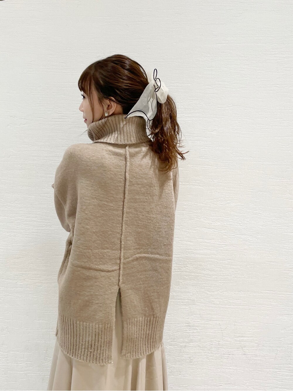 ブラウン系のブーツ、ホワイト系のスカート、ベージュ系のニット/セーターを着用したレディースの冬コーディネートの5枚目の写真