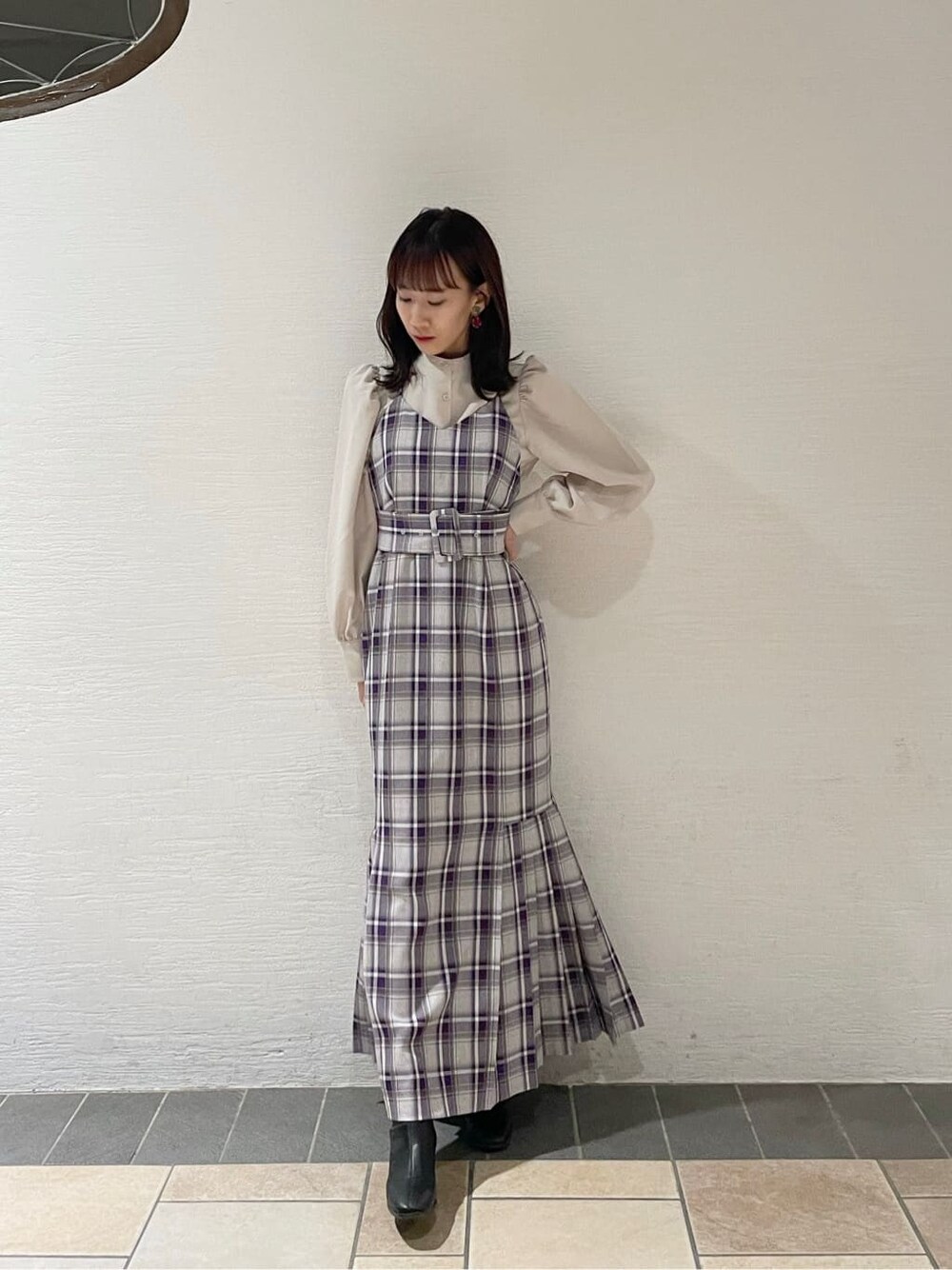 ブラック系のブーツ、ホワイト系のチェスターコート、パープル系のジャンパースカートを着用したレディースの冬コーディネートの3枚目の写真