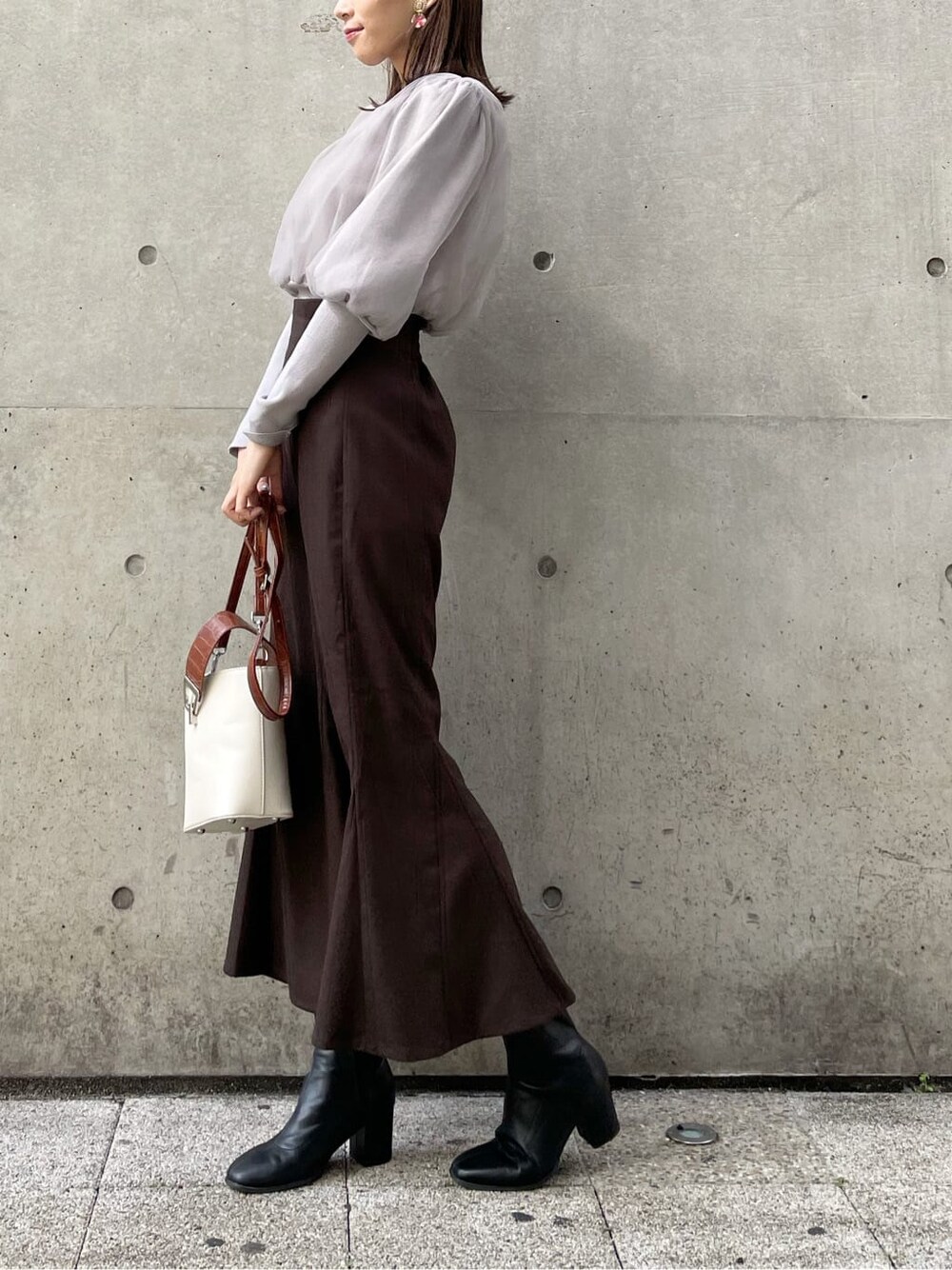 グレー系のニット/セーター、ブラック系のブーツ、ブラウン系のスカートを着用したレディースの秋コーディネートの3枚目の写真