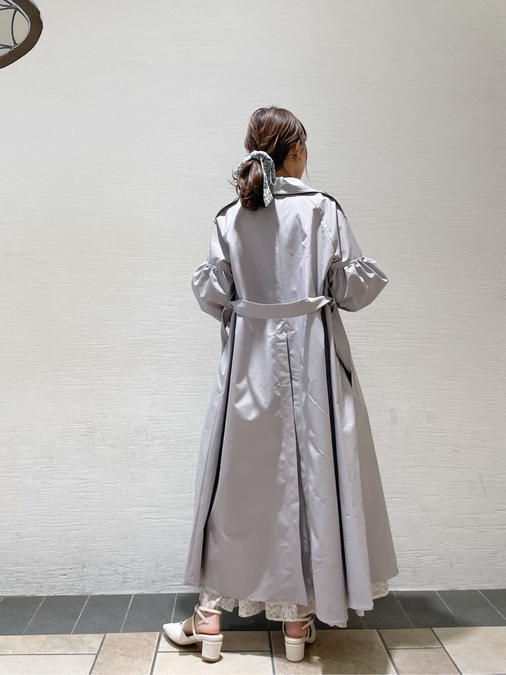 グレー系のトレンチコート、オレンジ系のワンピース、グレー系のニット/セーターを着用したレディースの冬コーディネートの5枚目の写真