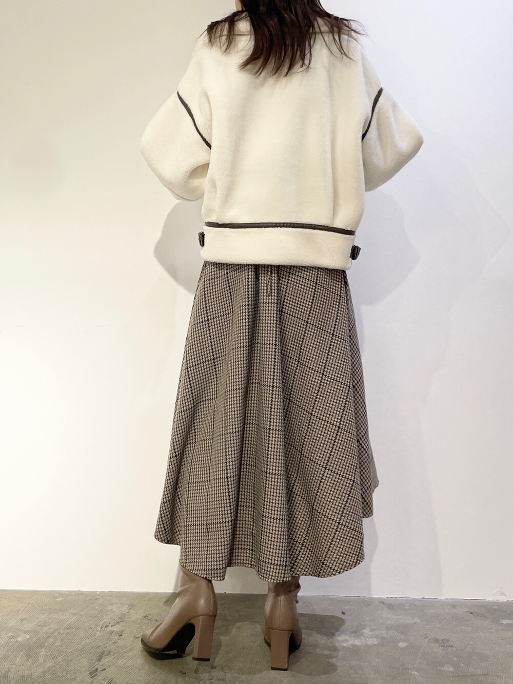 ブラウン系のワンピース、ベージュ系のブーツ、ホワイト系のブルゾンを着用したレディースの秋コーディネートの5枚目の写真