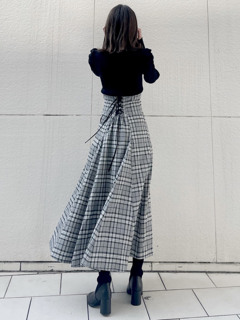 ブラック系のニット/セーター、グレー系のスカート、ブラック系のブーツを着用したレディースの秋コーディネートの2枚目の写真