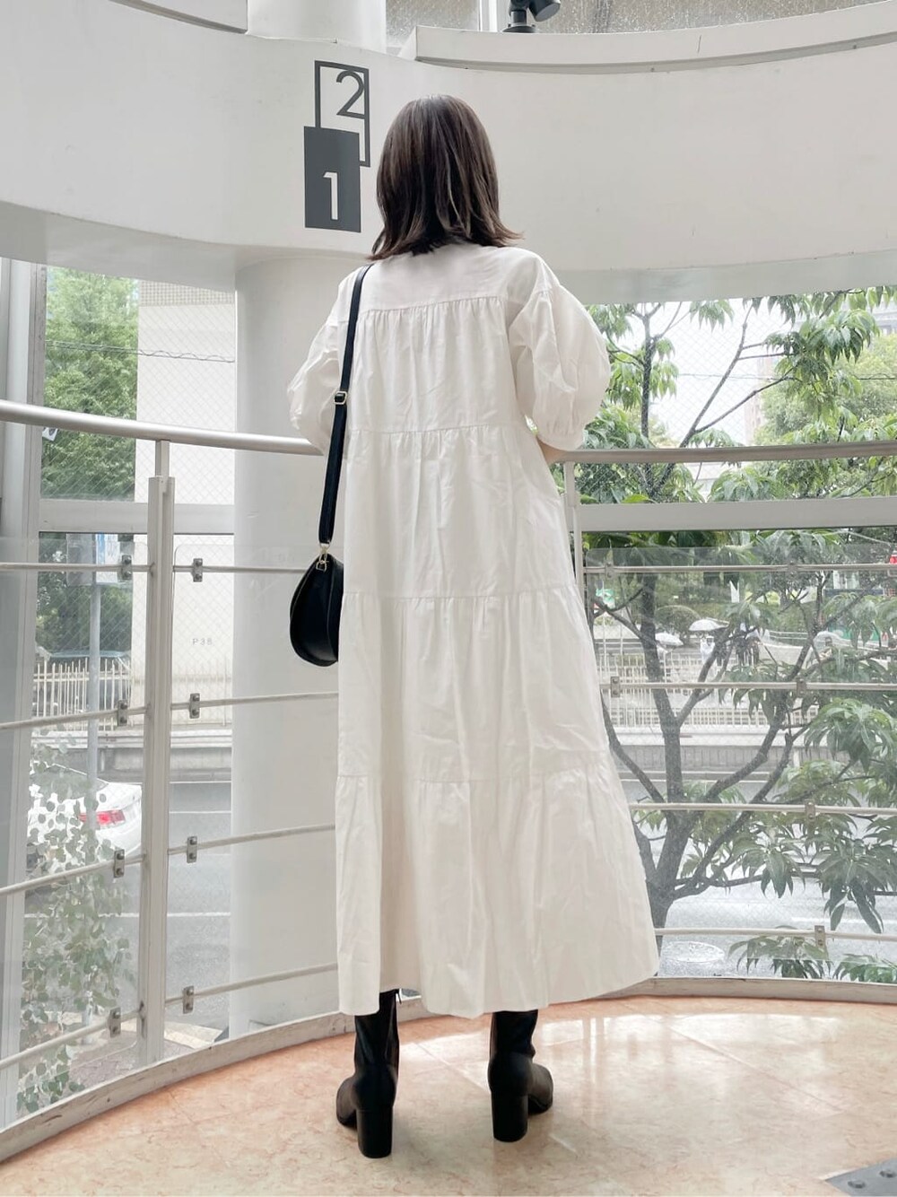 ホワイト系のワンピース、ブラック系のショルダーバッグ、ベージュ系のニット/セーターを着用したレディースの秋コーディネートの4枚目の写真