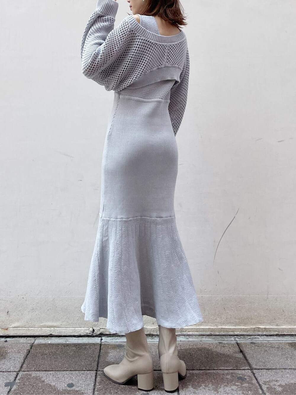 グレー系のワンピース、ホワイト系のハンドバッグ、ベージュ系のブーツを着用したレディースの秋コーディネートの3枚目の写真