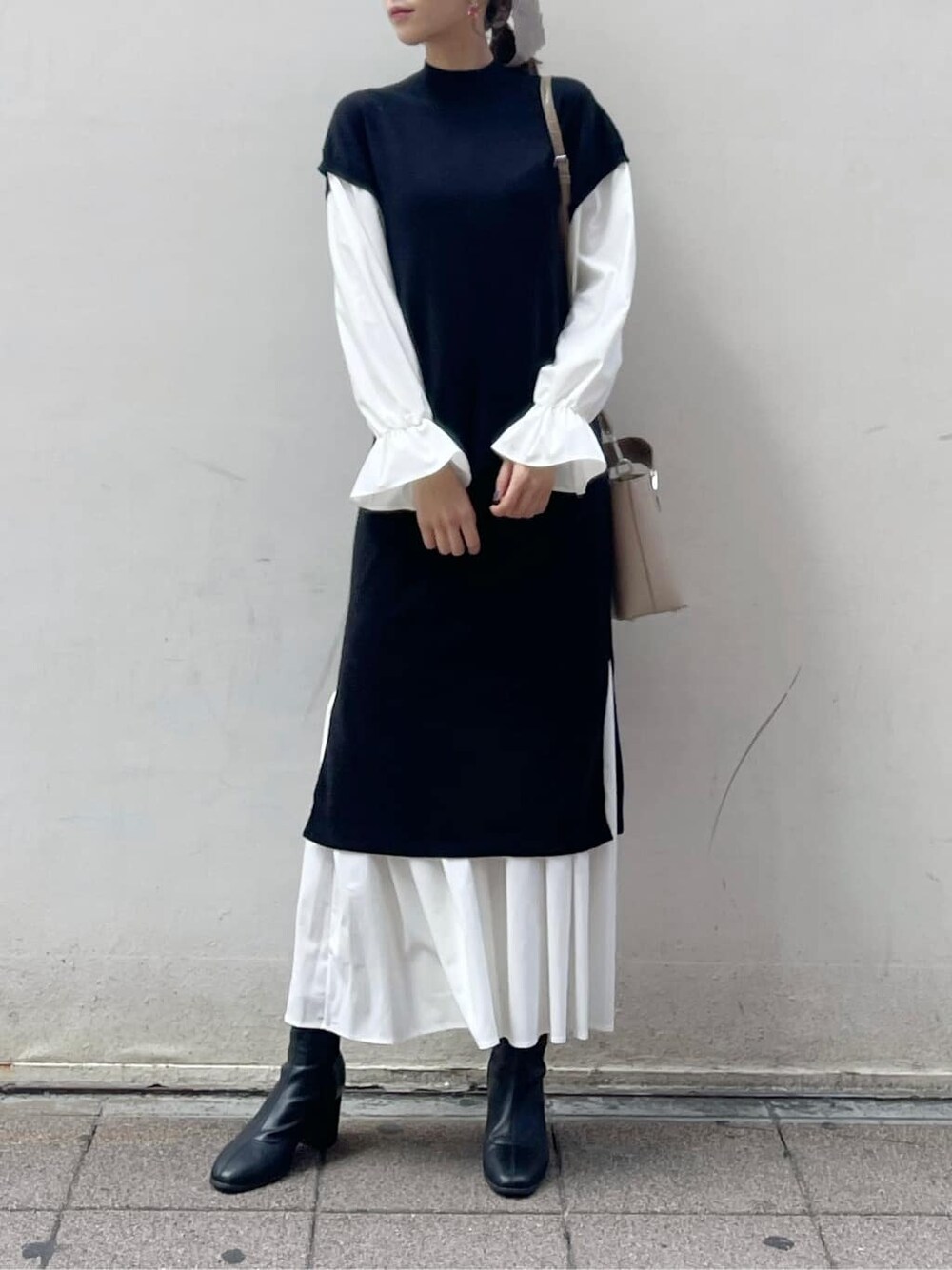 ブラック系のブーツ、ブラック系のワンピース、ベージュ系のハンドバッグを着用したレディースの秋コーディネートの4枚目の写真