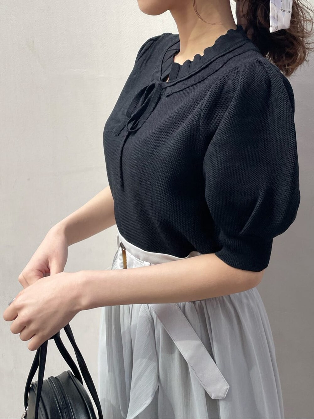 グレー系のスカート、ブラック系のサンダル、ホワイト系のニット/セーターを着用したレディースの春コーディネートの6枚目の写真