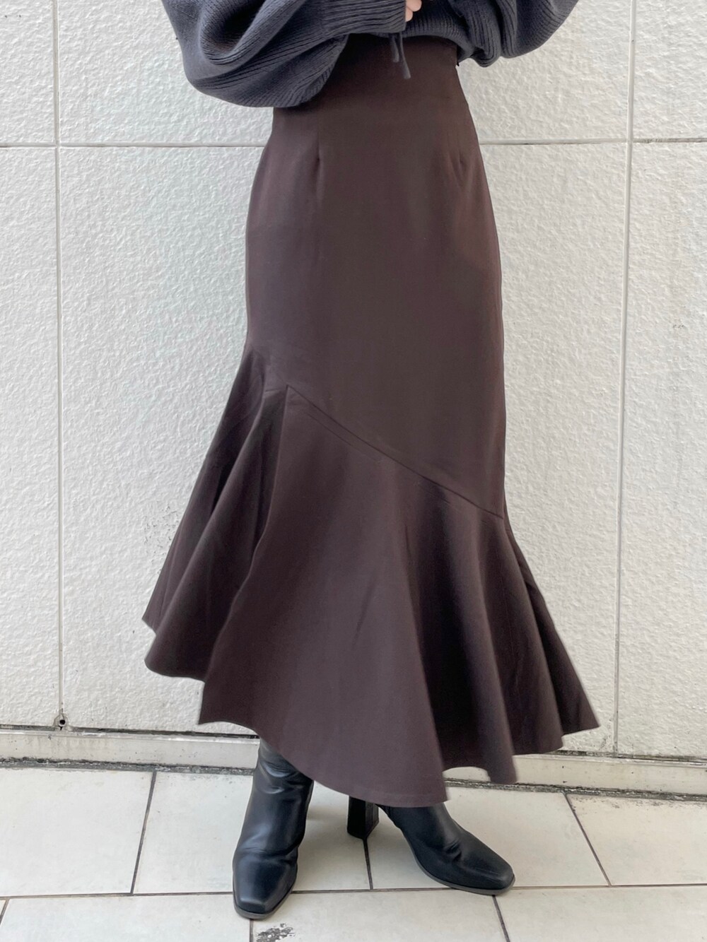 グレー系のニット/セーター、ブラウン系のスカート、ブラック系のブーツを着用したレディースの冬コーディネートの6枚目の写真