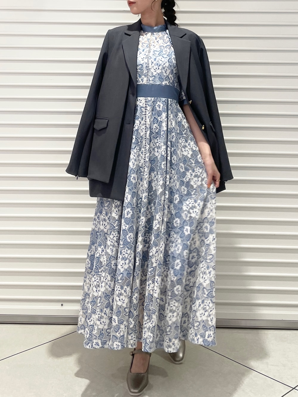 ブルー系のワンピース、シルバー系のパンプス、グレー系のテーラードジャケットを着用したレディースの冬コーディネートの2枚目の写真