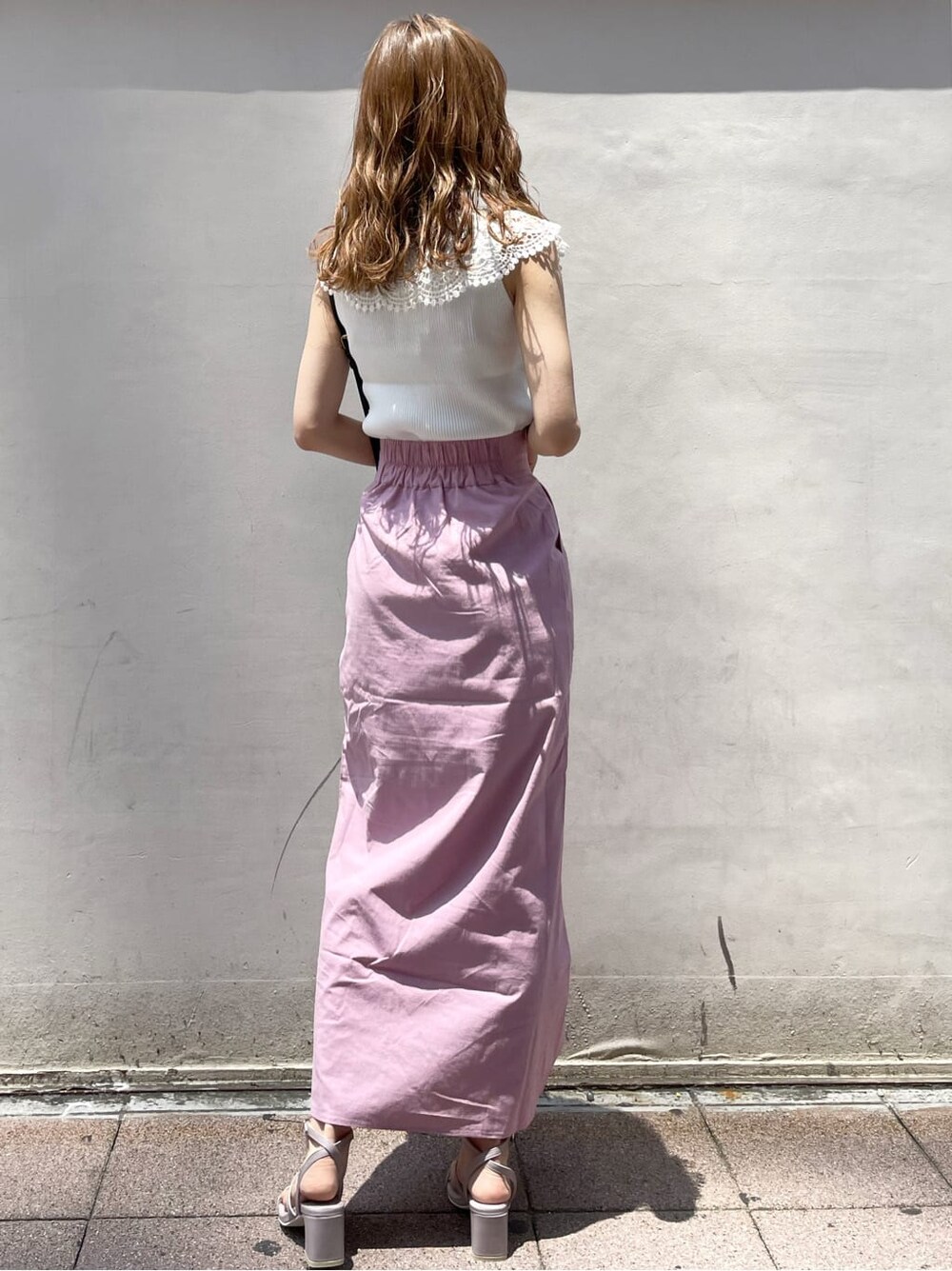 ブラック系のハンドバッグ、ピンク系のスカート、パープル系のサンダルを着用したレディースの夏コーディネートの4枚目の写真