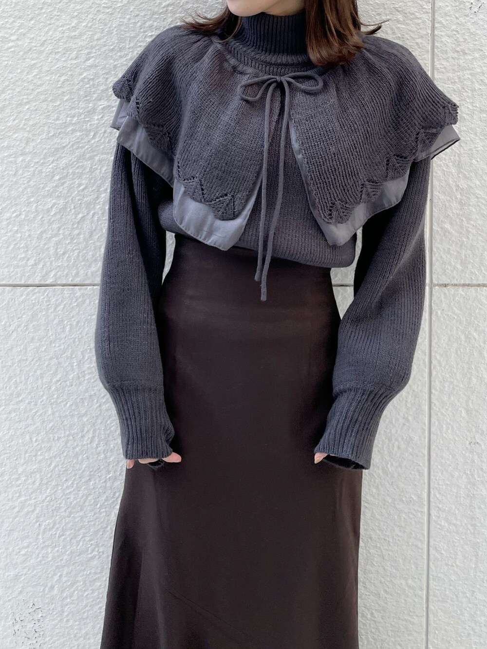 グレー系のニット/セーター、ブラウン系のスカート、ブラック系のブーツを着用したレディースの冬コーディネートの4枚目の写真