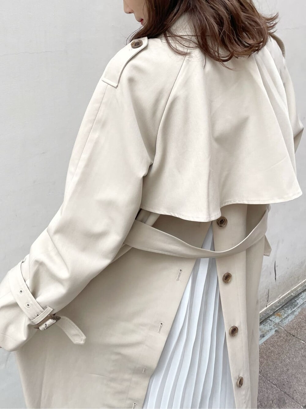 ベージュ系のトレンチコート、ホワイト系のワンピース、ベージュ系のブーツを着用したレディースの春コーディネートの4枚目の写真