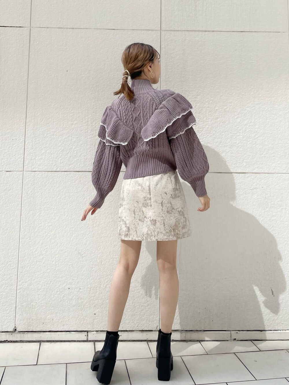 ベージュ系のスカート、ブラック系のブーツ、パープル系のニット/セーターを着用したレディースの秋コーディネートの3枚目の写真