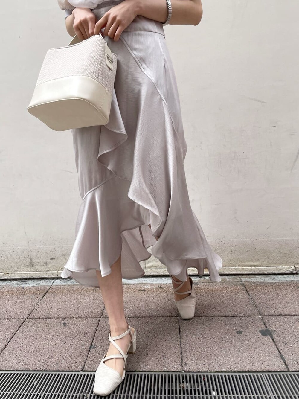 パープル系のニット/セーター、グレー系のスカート、ホワイト系のパンプスを着用したレディースの春コーディネートの7枚目の写真