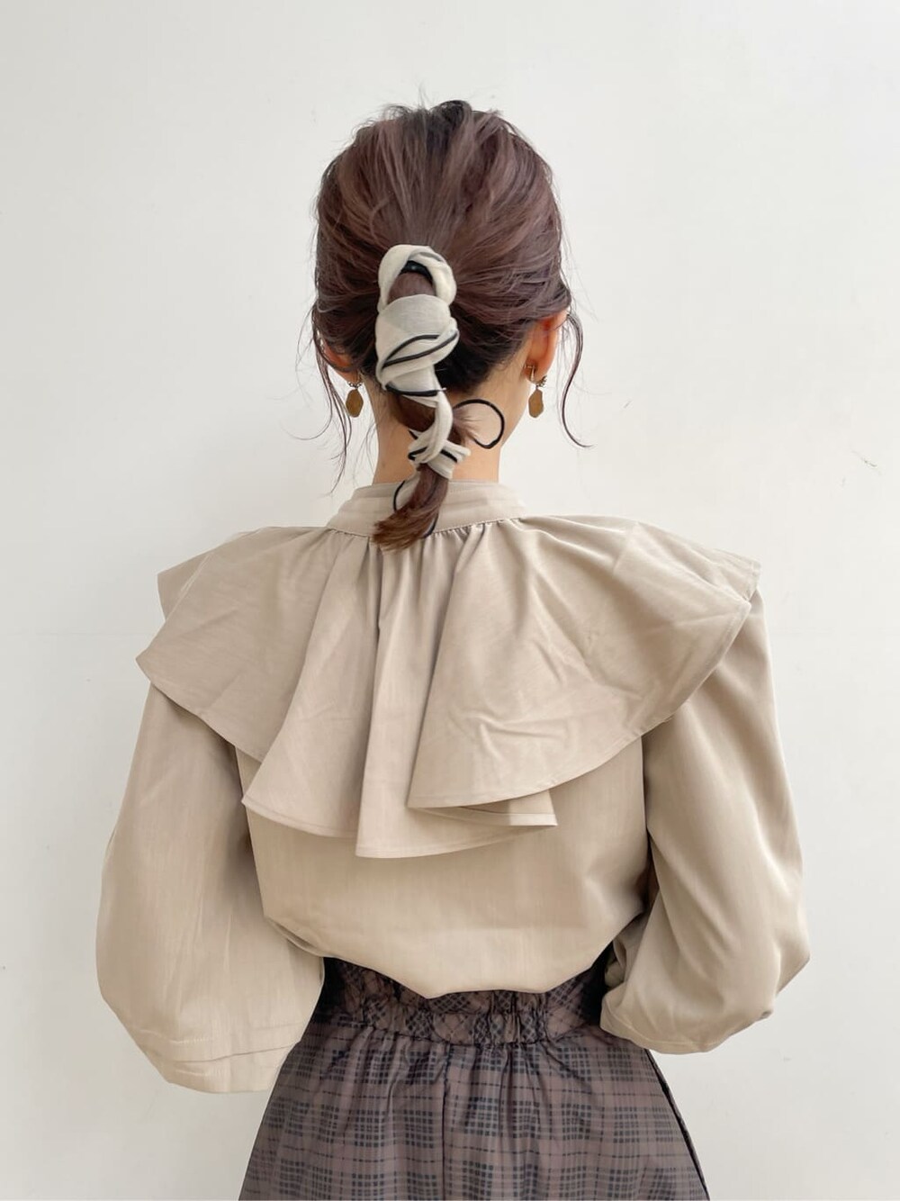 ブラック系のブーツ、ブラウン系のスカート、ベージュ系のシャツ/ブラウスを着用したレディースの冬コーディネートの5枚目の写真