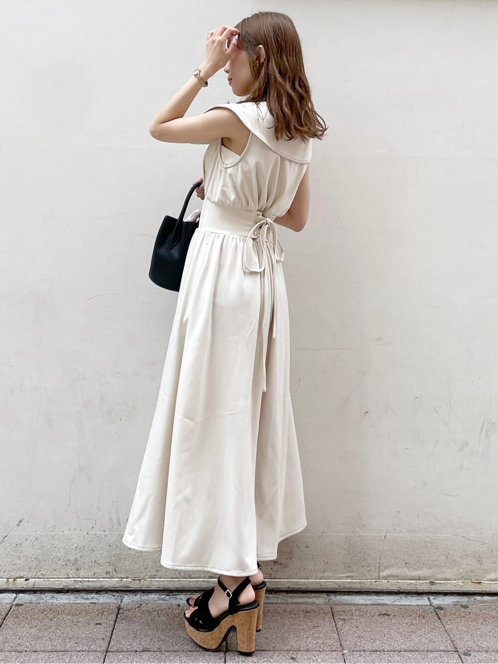 ブラック系のサンダル、ブラック系のハンドバッグ、ホワイト系のワンピースを着用したレディースの春コーディネートの3枚目の写真