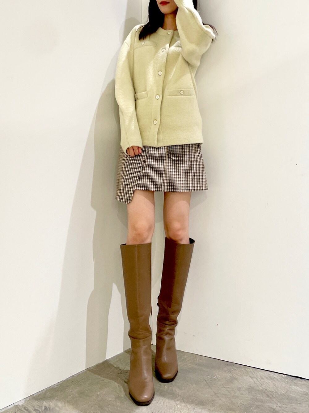 グリーン系のカーディガン/ボレロ、ブラウン系のスカート、ベージュ系のブーツを着用したレディースの秋コーディネートの2枚目の写真