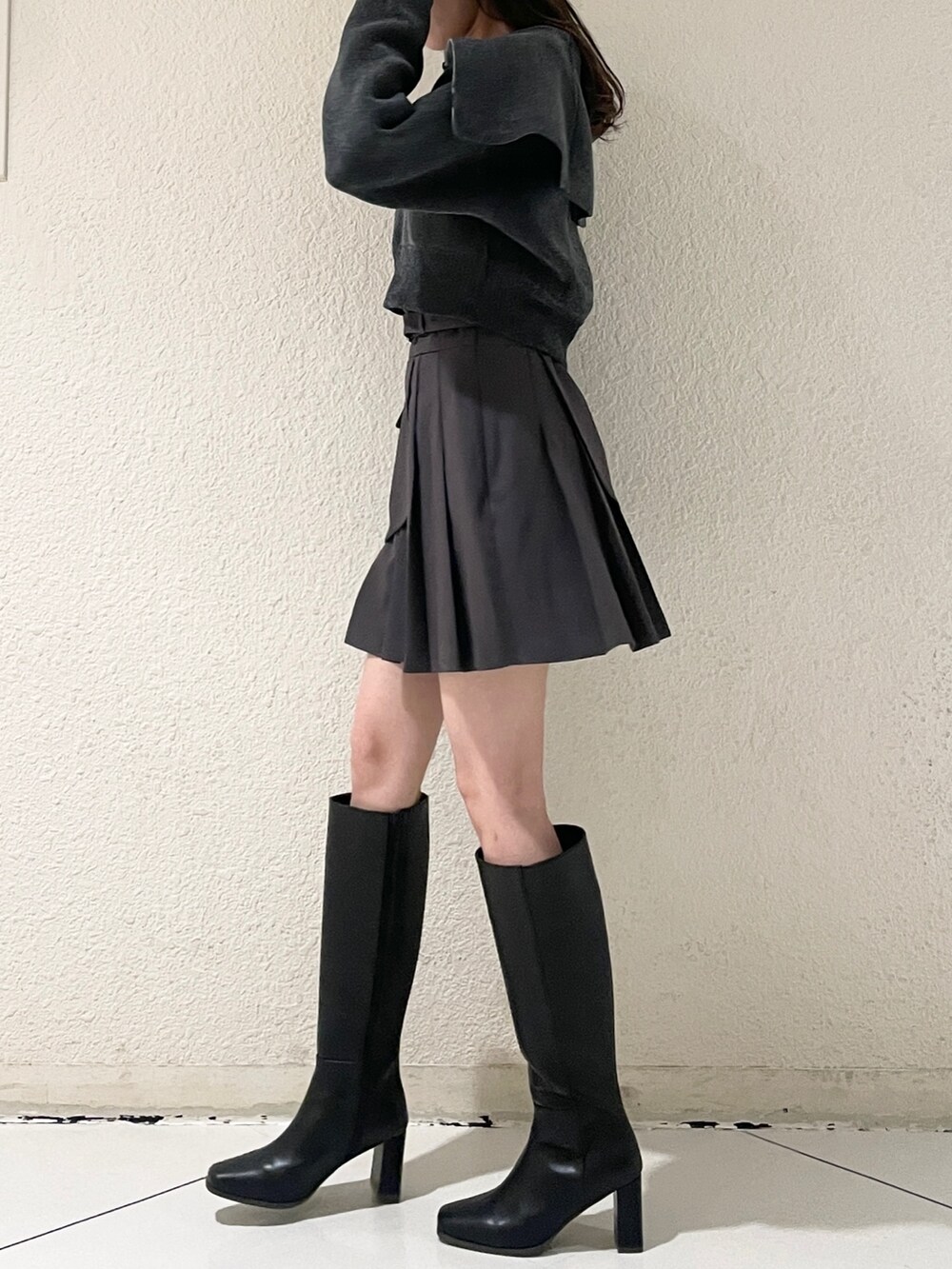 グレー系のニット/セーター、グレー系のスカート、ブラック系のブーツを着用したレディースの秋コーディネートの5枚目の写真