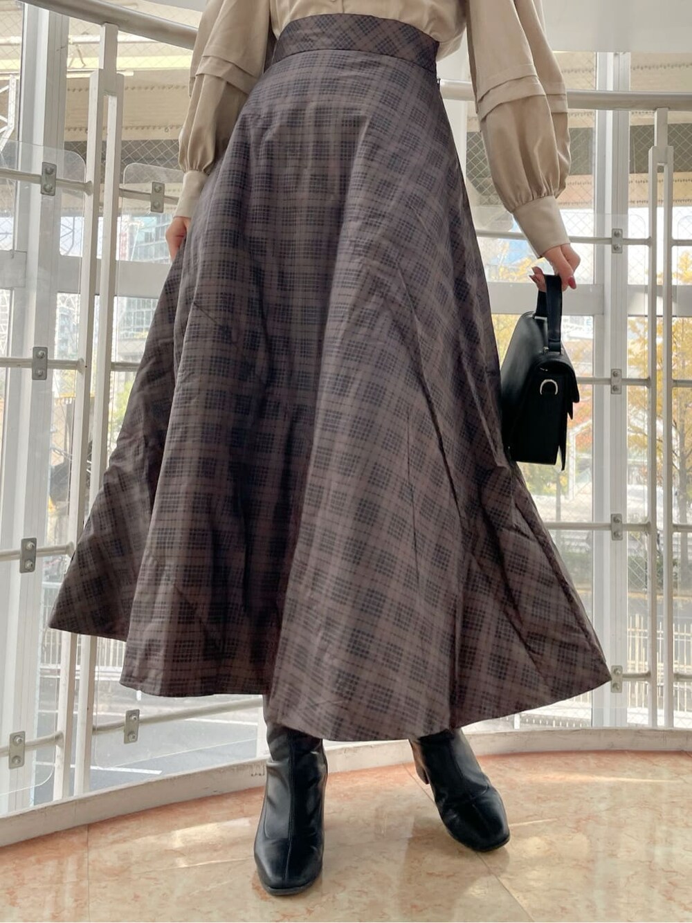 ブラック系のブーツ、ブラウン系のスカート、ベージュ系のシャツ/ブラウスを着用したレディースの冬コーディネートの9枚目の写真